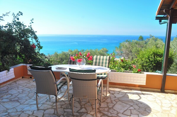 Une terrasse extérieure avec une table et des chaises, offrant une vue panoramique sur l’océan.