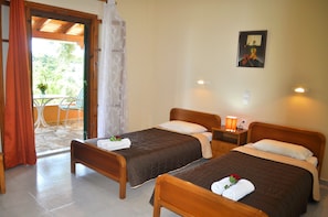 Two single beds with brown bedspreads and white pillows, a wooden headboard, and a nightstand with a lamp.