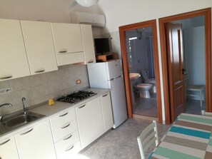 A kitchen with white cabinets, a gas stove, a sink, and a refrigerator.