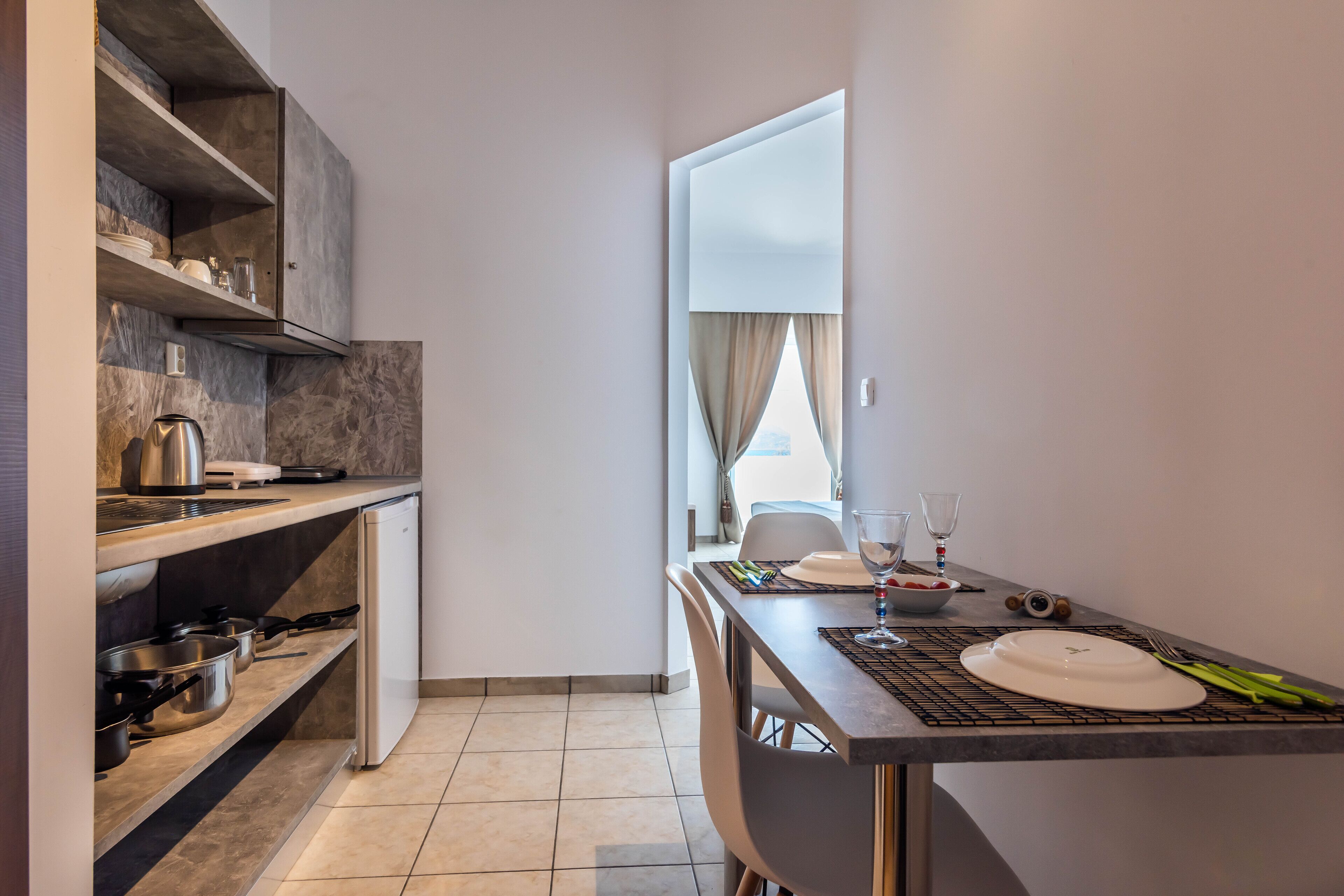 A modern kitchen with a built-in oven, a coffee machine, and a dining area with a table set for two.