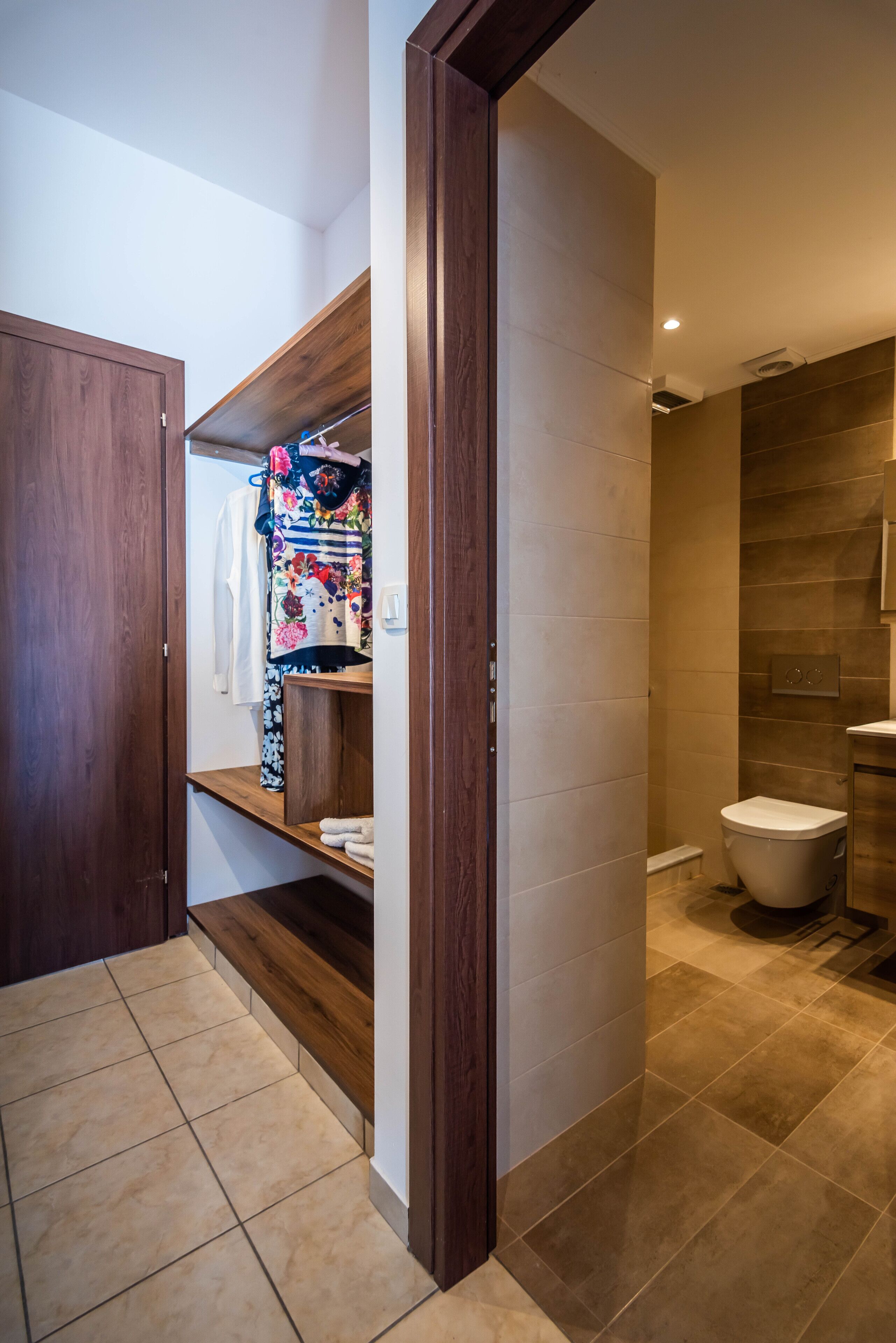 A modern bathroom with a toilet, a shower area, and a wooden vanity with a towel rack.