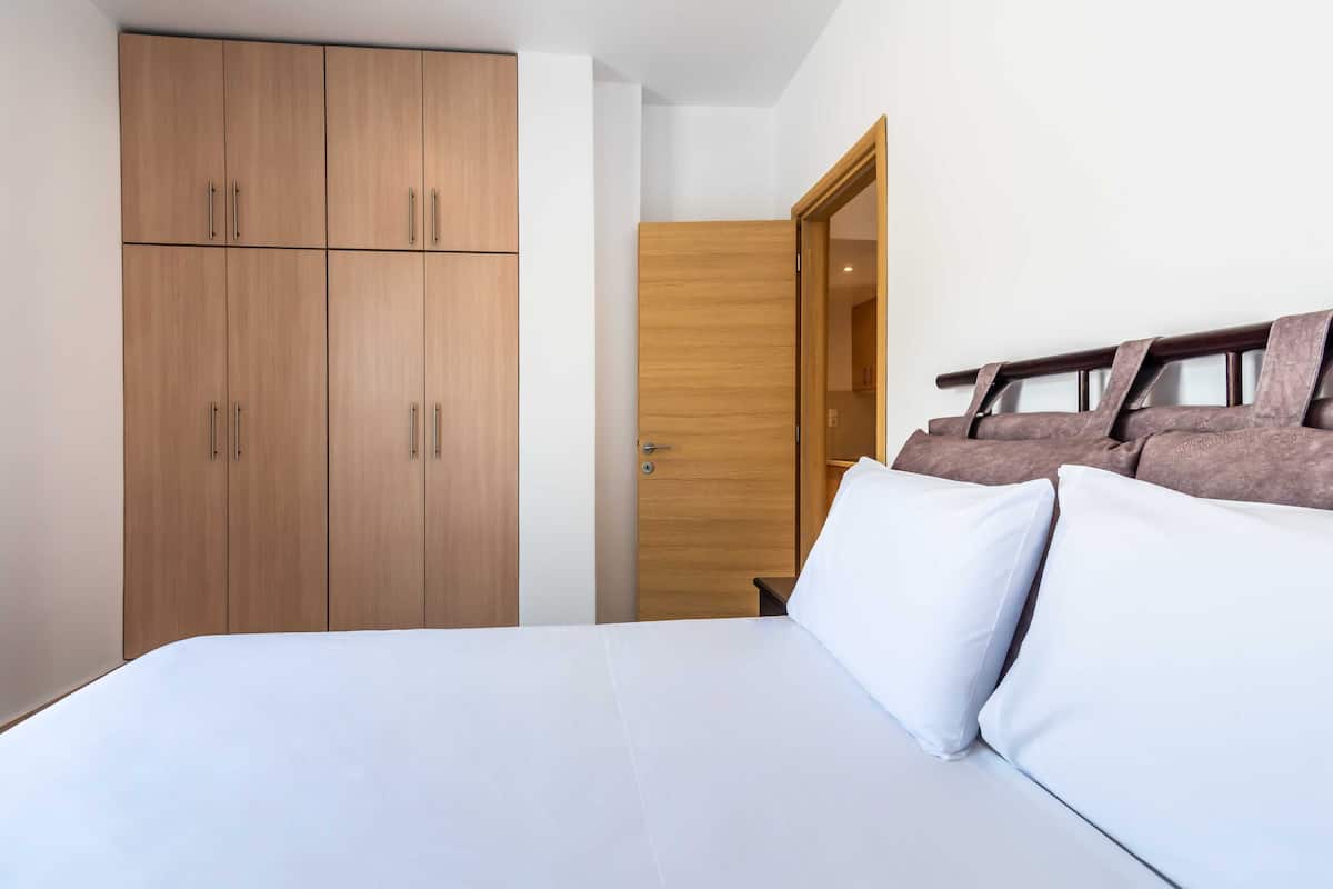 A bedroom with a bed, wooden wardrobe, and a wooden door.
