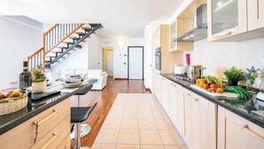 A modern kitchen with wooden cabinets, a black countertop, and a staircase leading to another room. - Penthouse The Magnifique View in Stresa (Stresa)