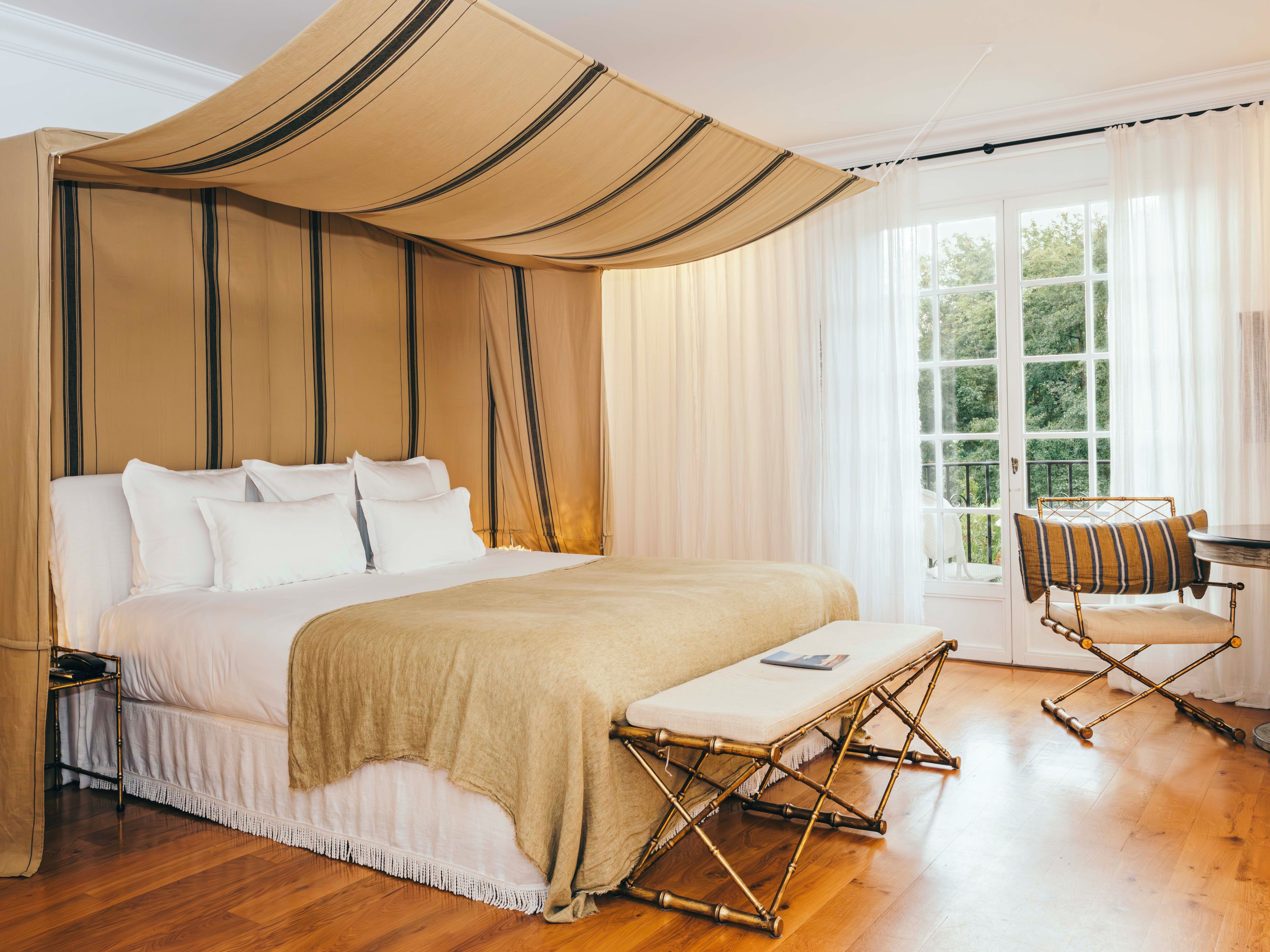 Un dormitorio amplio con una cama grande, una mesita de noche, una silla y una ventana con vistas a zonas verdes.