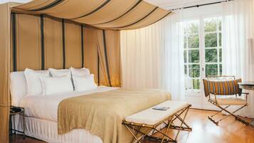 Un dormitorio amplio con una cama grande, una mesita de noche, una silla y una ventana con vistas a zonas verdes.
