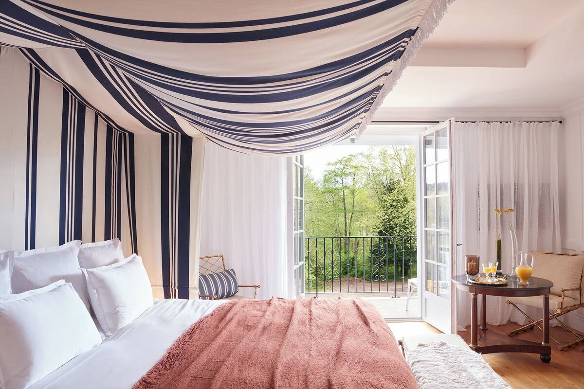 A bedroom with a bed, a balcony, and a table with drinks.