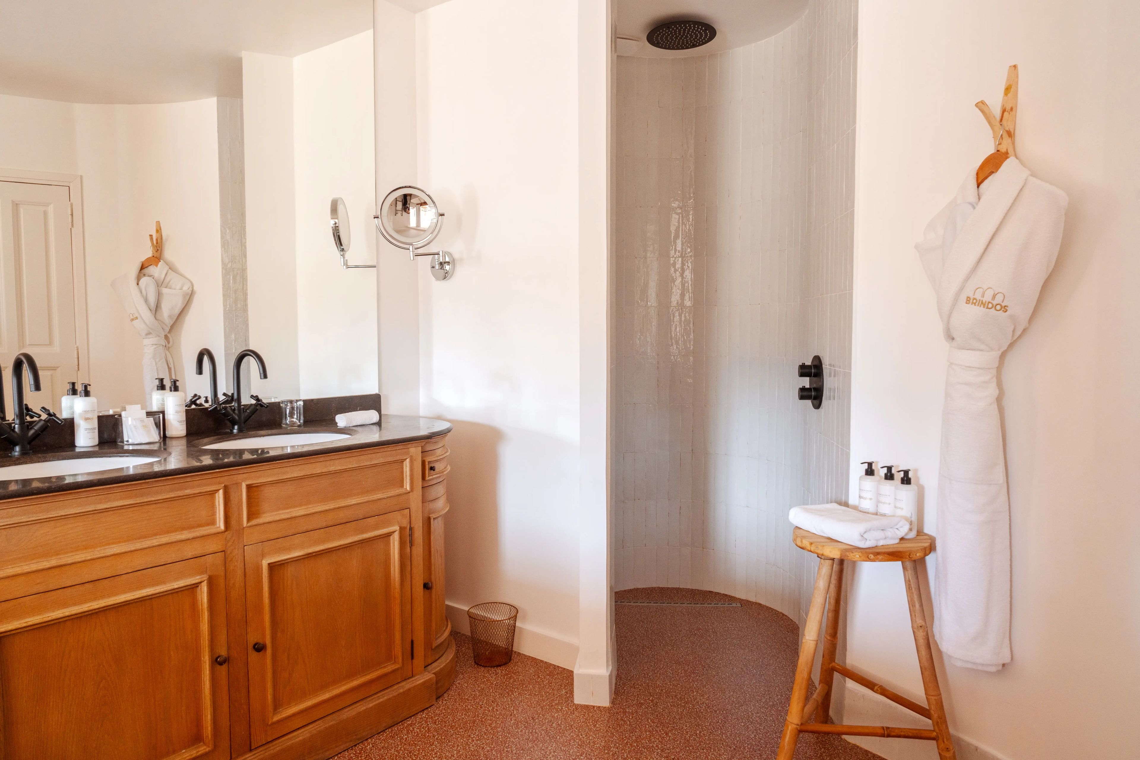 Une salle de bain avec des meubles en bois, un double vasque, un miroir et un espace douche.