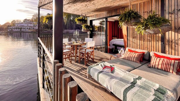 A wooden deck with a sofa and chairs, a dining table, and hanging plants. - Brindos Lac & Château (Anglet)