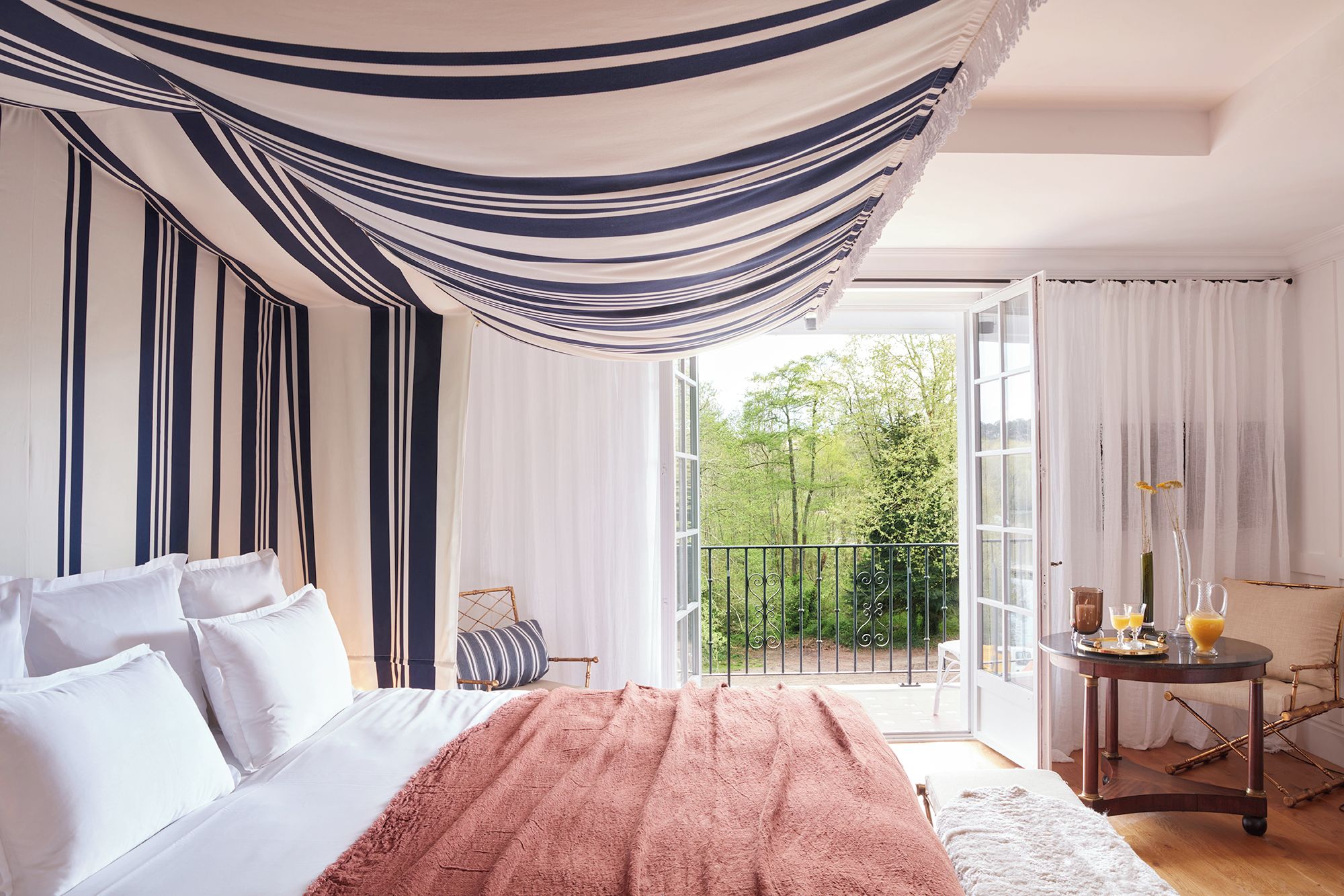 Un dormitorio con cama, balcón y una mesa con bebidas.