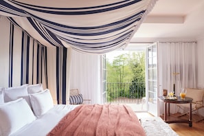 A bedroom with a bed, a balcony, and a table with drinks.