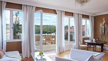 A spacious living room with a large window, a dining area with a table and chairs, and a view of the outdoors.