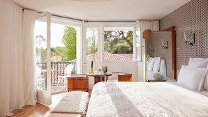Un dormitorio con una cama grande, una mesita y un balcón con vistas al exterior.