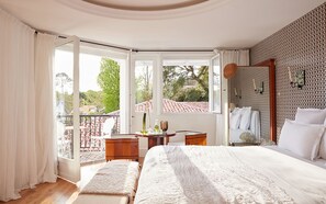 Un dormitorio con una cama grande, una mesita y un balcón con vistas al exterior.