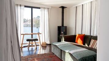 A living room with a view of a body of water, a sofa, a bench, and a rug.