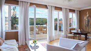 A spacious living room with a large window, a dining area with a table and chairs, and a view of the outdoors. - Brindos Lac & Château (Anglet)