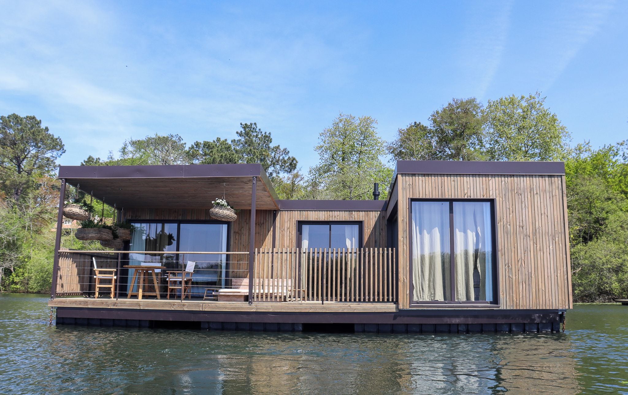 Una casa flotante con terraza, comedor y un gran ventanal.