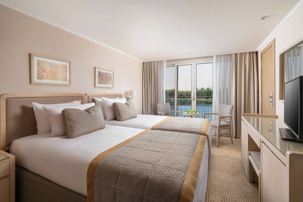 Une chambre d’hôtel avec deux lits, une télévision, un bureau et un balcon avec vue.