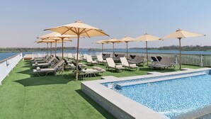 A rooftop pool area with multiple sun loungers and umbrellas, a clear view of the water, and a tiled pool edge. - JAZ  Elite Viceroy Nile Cruise - Every Saturday from Luxor for 07 & 04 Nights - Every Wednesday From Aswan for 03 Nights (Luxor)