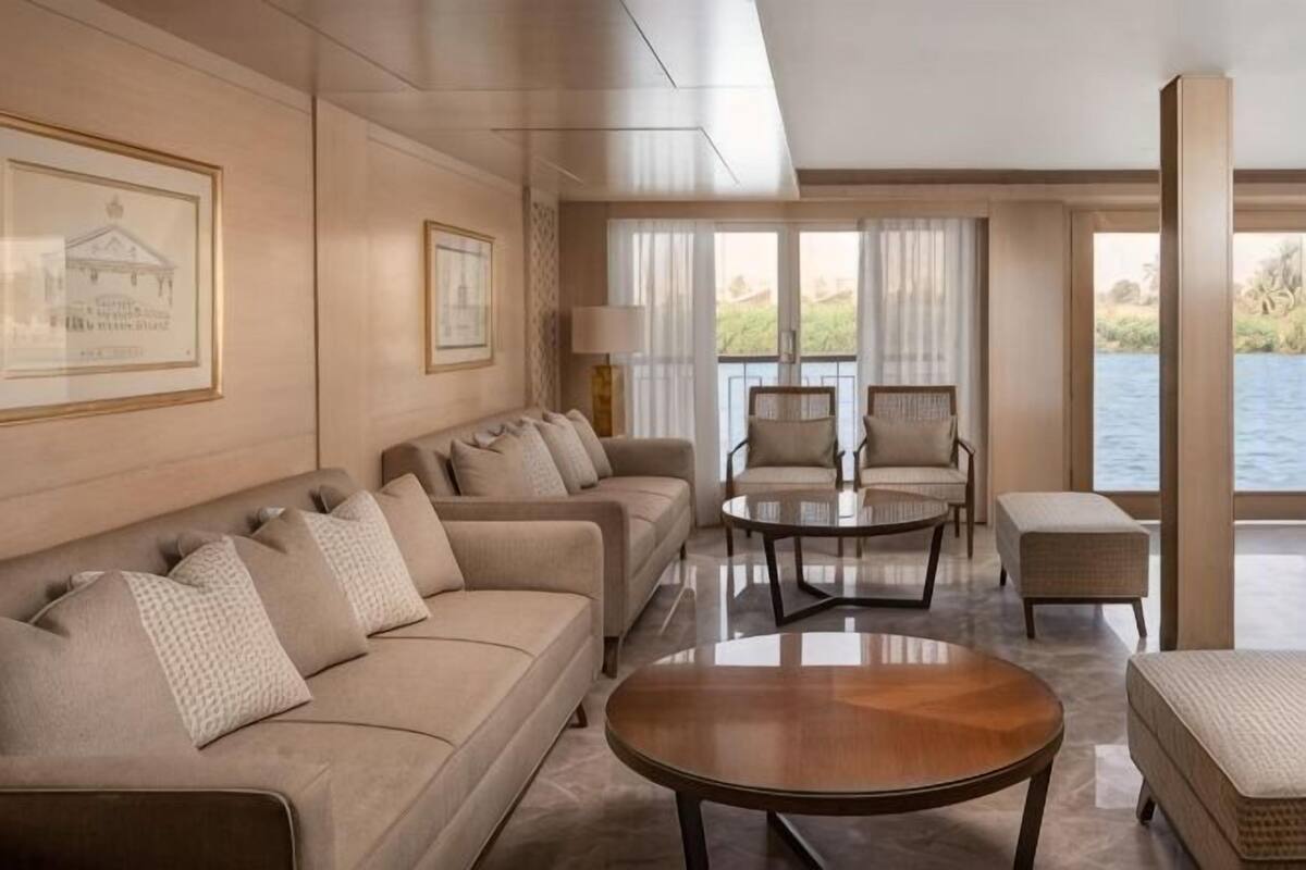 Un salon spacieux comprenant un ensemble de canapés, une table basse et donnant sur un plan d’eau.