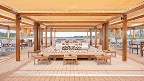 A covered outdoor seating area with wooden furniture, a central sofa, and a view of the sea. - JAZ  Elite Viceroy Nile Cruise - Every Saturday from Luxor for 07 & 04 Nights - Every Wednesday From Aswan for 03 Nights (Luxor)