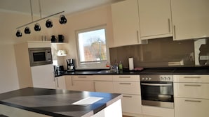 A modern kitchen with a large island, built-in oven, and a window providing natural light.