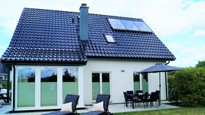 A house with a tiled roof, a chimney, and a patio with a table and chairs.