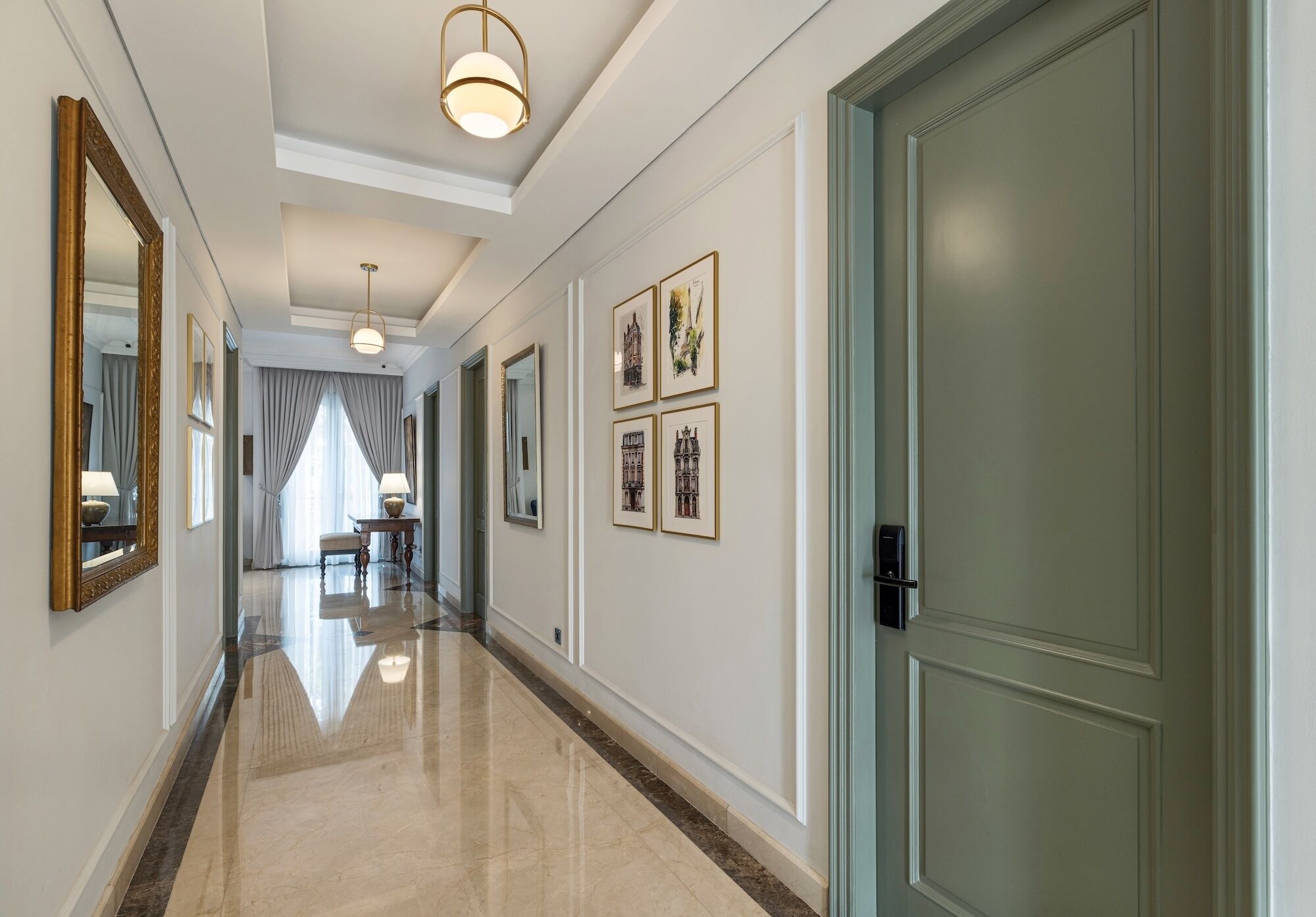 A hallway with a polished floor, framed artwork on the walls, and a door on the right.