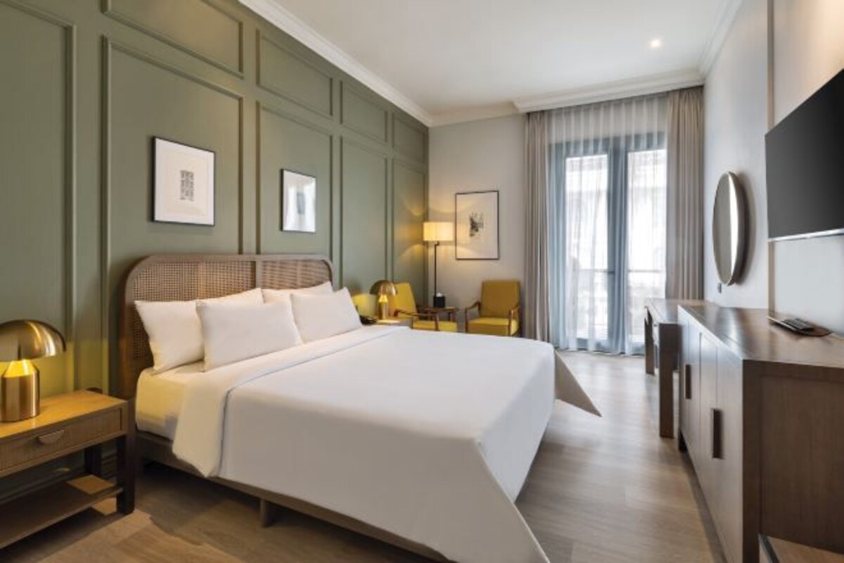 Camera d'albergo con un letto grande, una scrivania, una sedia e una televisione.