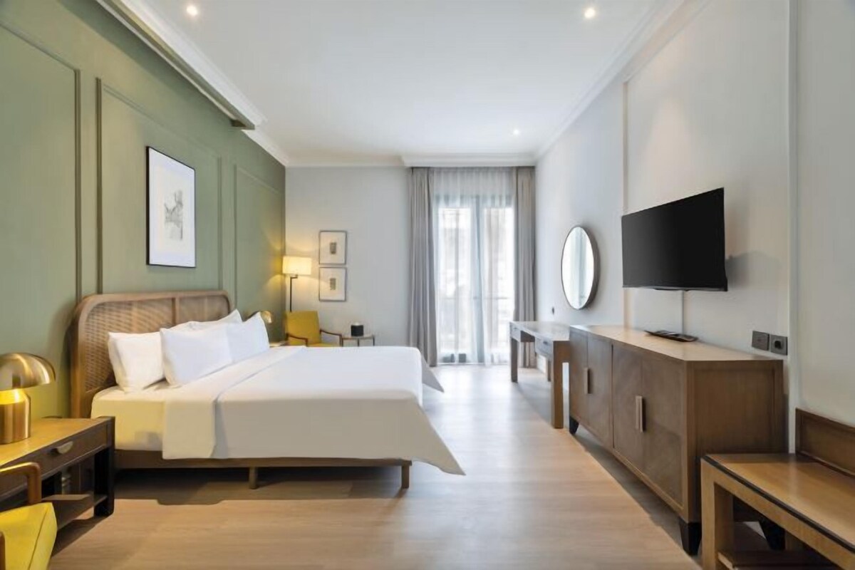 Una camera d'albergo con un letto grande, comodini, una scrivania, una televisione e uno specchio.