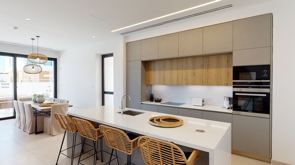 Una cucina moderna con isola centrale, sgabelli da bar e elettrodomestici integrati.