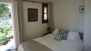 Relax in a spacious bedroom with a large bed and a stylish window with curtains, featuring a beautiful framed artwork above.