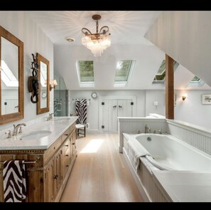 Bathroom features a bathtub, double vanity, and wooden cabinet.