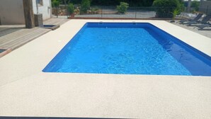 Una piscina rettangolare con un'area prendisole chiara tutt'intorno.