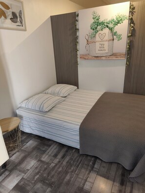 Une chambre à coucher comprenant un lit, une petite table, une étagère fixée au mur et un élément décoratif mural.