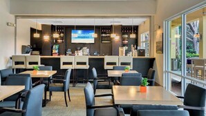 A restaurant with multiple tables and chairs, a bar area with shelves of bottles, and a large screen displaying a beach scene. - Encantada - 4 bed 3 bath lakefront corner house (Kissimmee)
