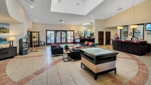 A spacious lobby with a reception desk, seating area, and a large glass-top table. - Encantada - 4 bed 3 bath lakefront corner house (Kissimmee)