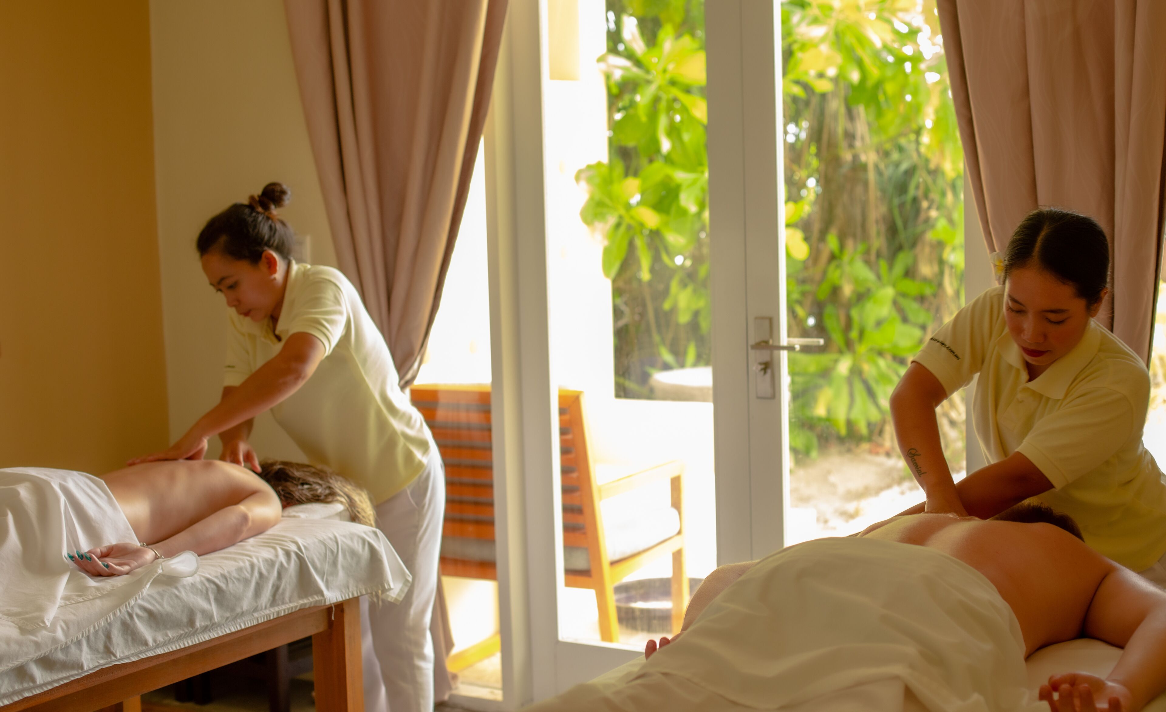 Une salle de massage où deux thérapeutes s'occupent des clients.