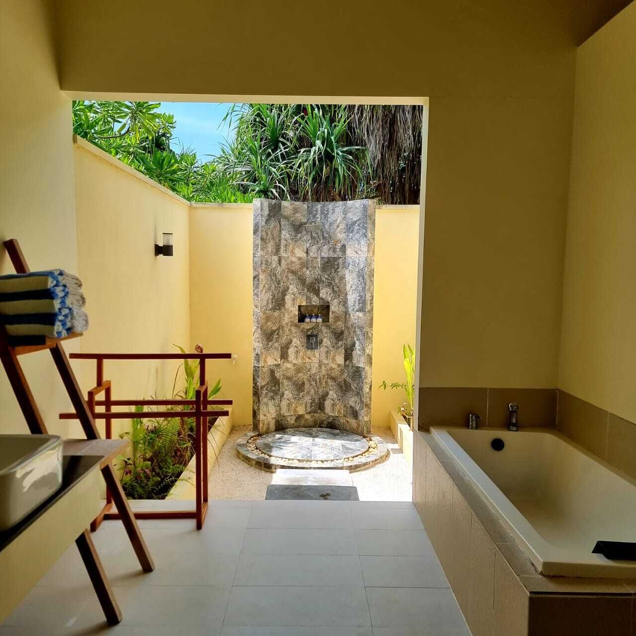 Un baño con ducha de piedra, bañera y zona de estar con una toalla.