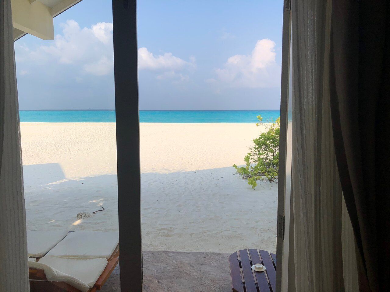 A view from a room with a beach visible through a window.