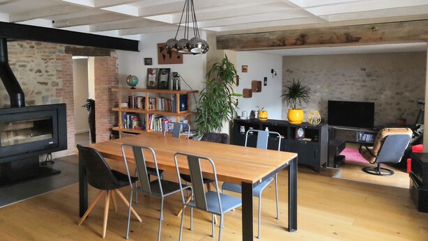 Een moderne woonkamer met een houten eettafel, metalen stoelen, een open haard, een boekenkast en een televisie.