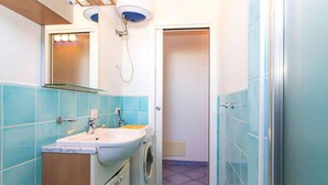 Un baño pequeño con lavamanos, espejo y lavadora.