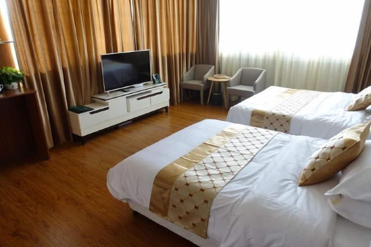Quarto de hotel com duas camas, televisão, secretária e uma cadeira.