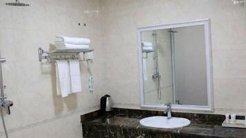 A bathroom with a marble countertop, a sink, a mirror, and a shower.