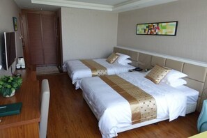 Ein Hotelzimmer mit zwei Betten, Holzboden, Schreibtisch mit Stuhl, Fernseher und einem an der Wand hängenden Gemälde.