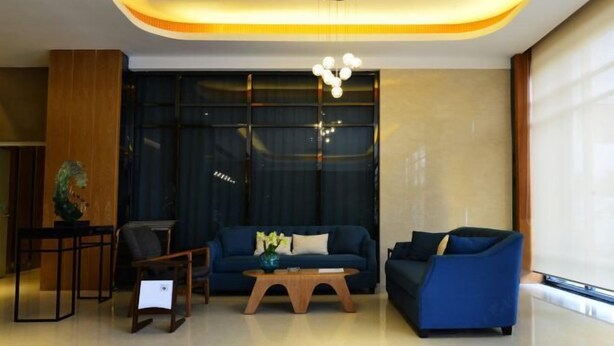 A modern living room with a sofa, coffee table, and a decorative vase. - Changtai 8090 Hotel (Zhangzhou)