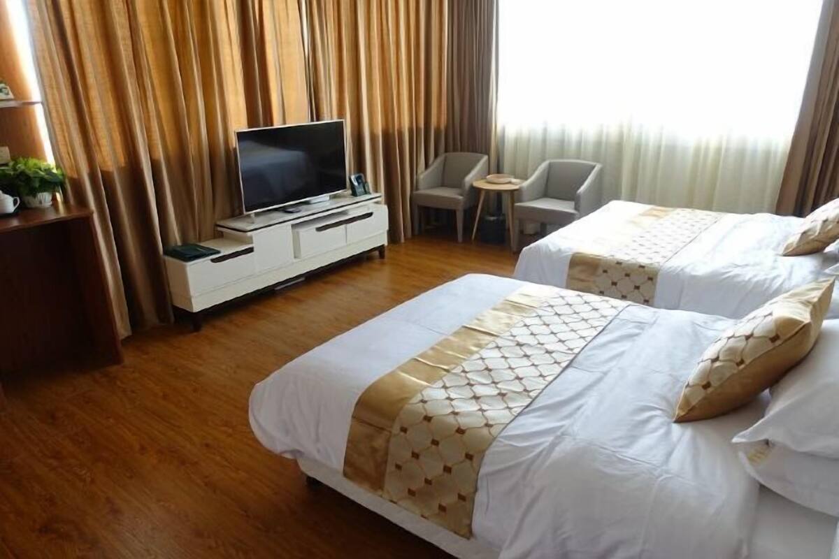 Quarto de hotel com duas camas, televisão, mesa pequena e uma cadeira.