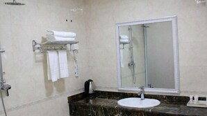 A modern bathroom with a marble countertop, a white sink, a large mirror, and a shower with a glass enclosure. - Changtai 8090 Hotel (Zhangzhou)