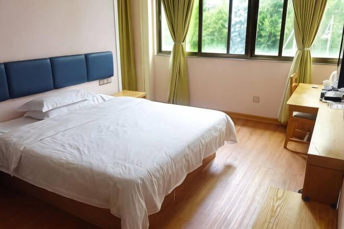 Um quarto com uma cama, uma escrivaninha e uma janela com cortinas.