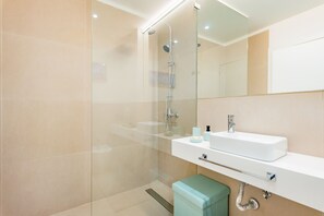 A modern bathroom with a glass shower enclosure, a white sink, and a mirror above the sink.