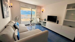 Een moderne woonkamer met een bank, een televisie en een balkon met uitzicht.